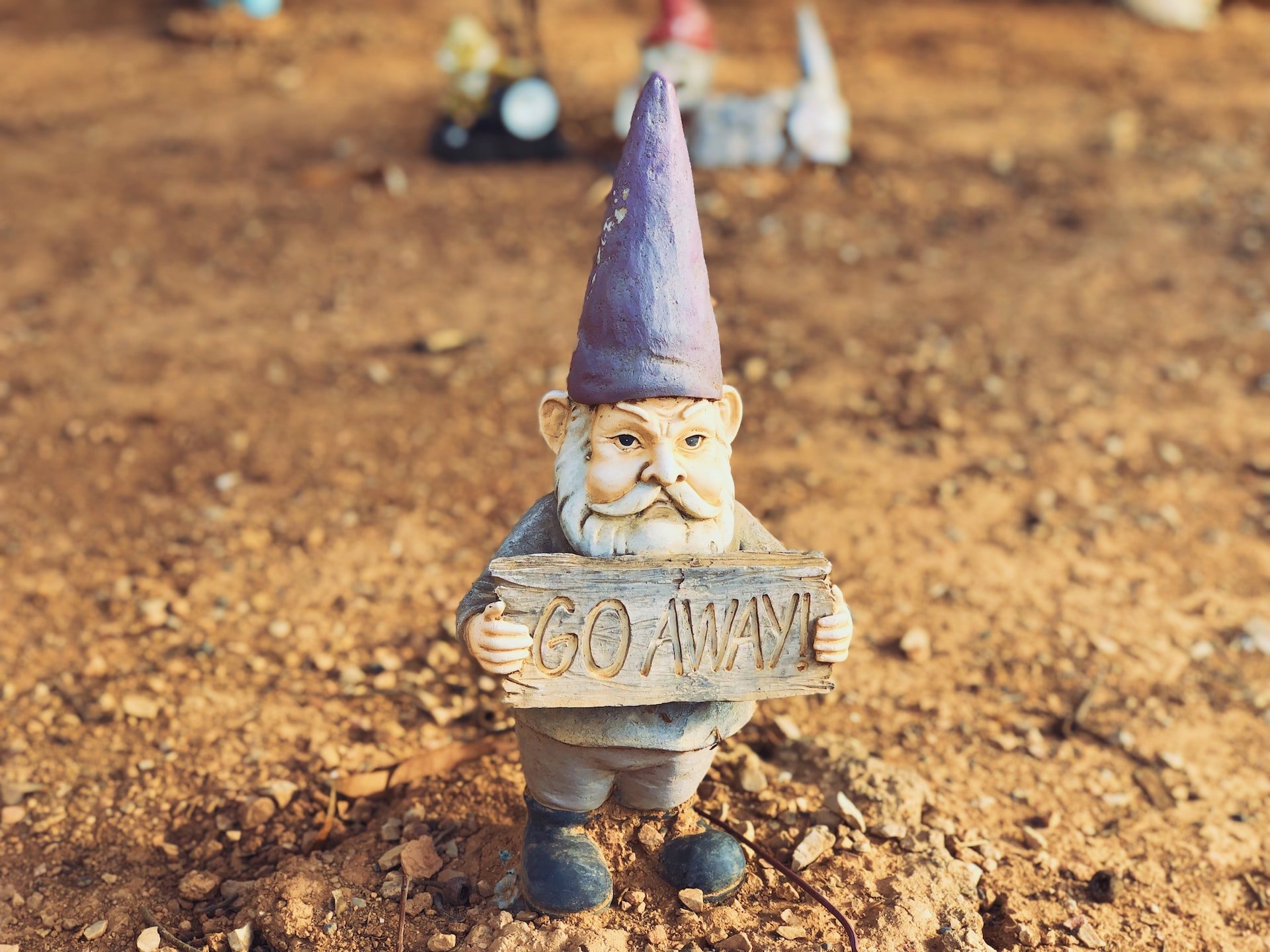 A gnome holding a sign that says 'go away'