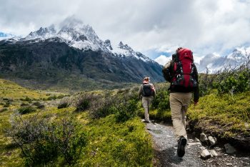 Two people hiking near mountains.